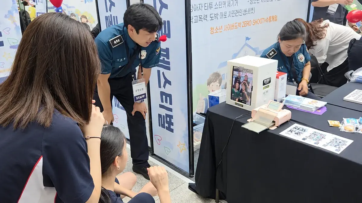 Police officers and students taking photos with a my4cut mini booth at a youth campaign event